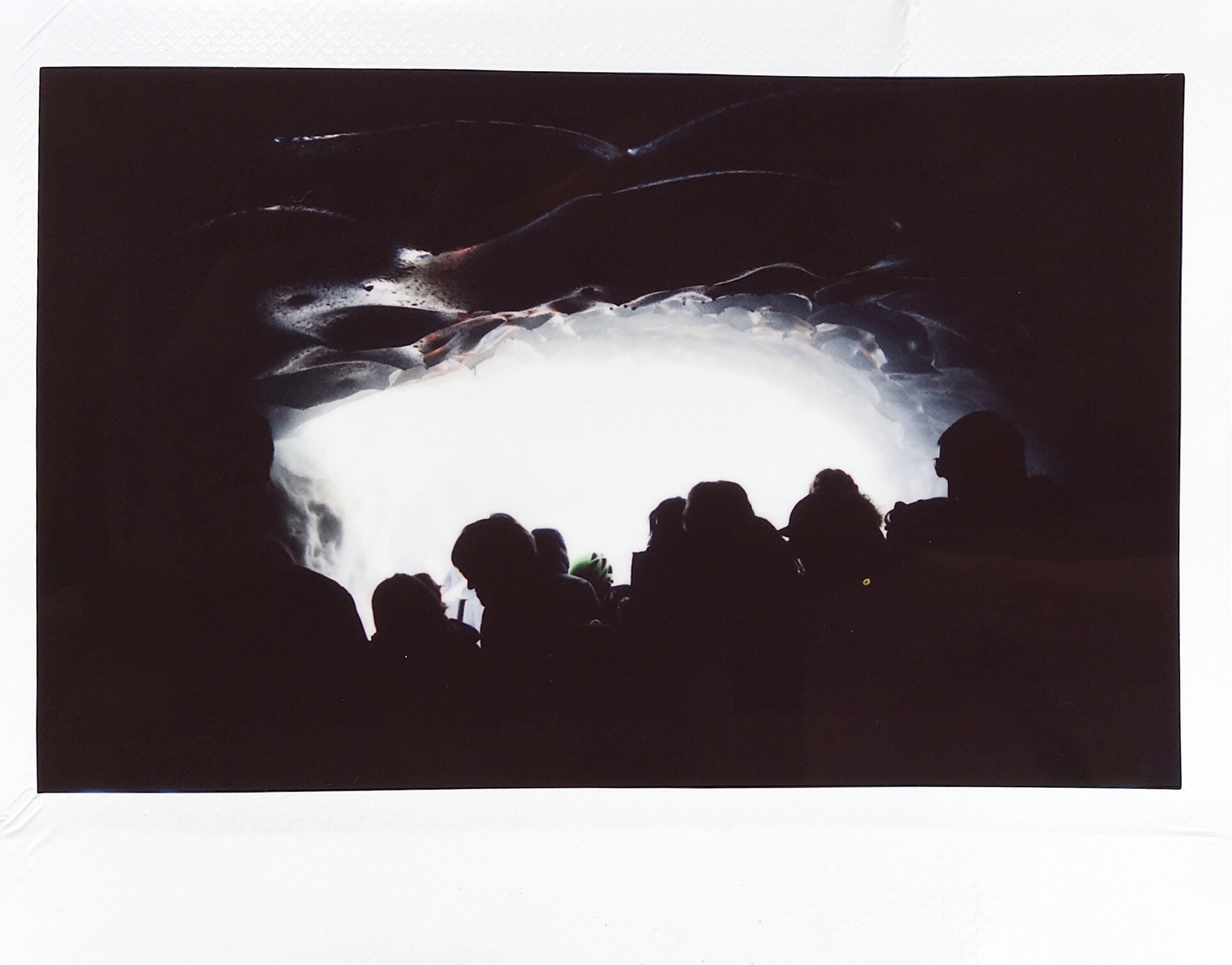 Photograph of the silhouette of people in an icy cave